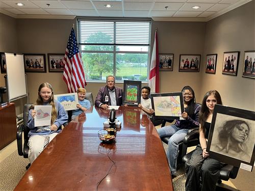 five student art winners around table with Dr. Nichols